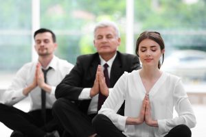 Tame Your Triggers. Business people relaxing in meditation pose in office